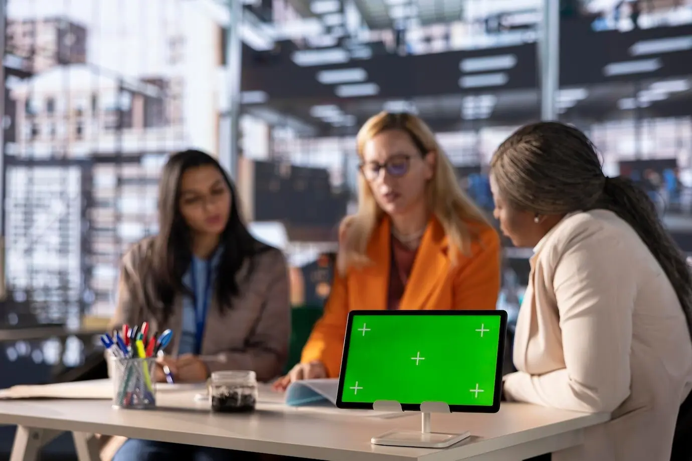 Разнообразные женщины-бизнесмены разрабатывают стратегию в профессиональном офисе с зеленым экраном.