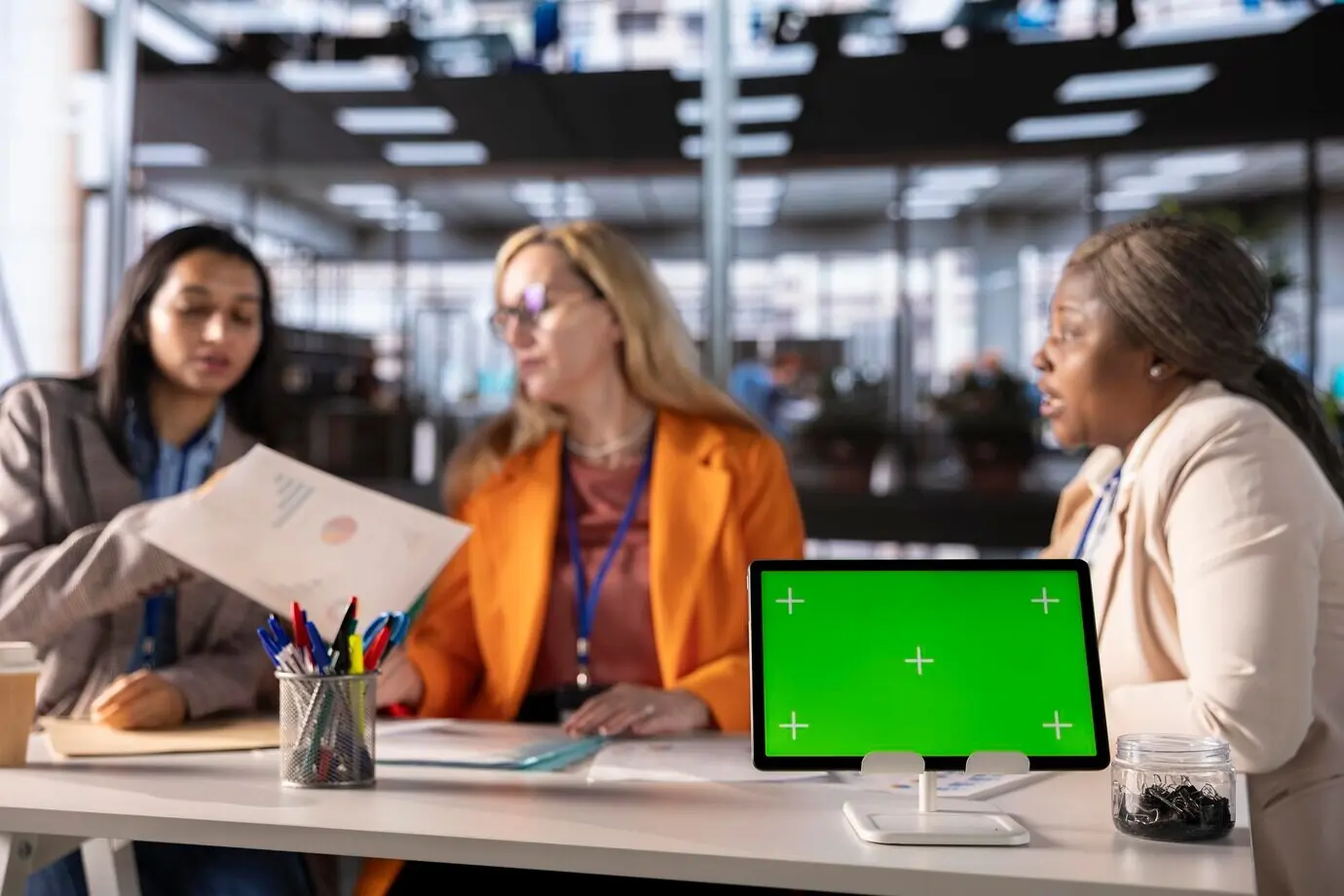 Деловые женщины разных этнических групп работают рядом с изолированным зелёным экраном.
